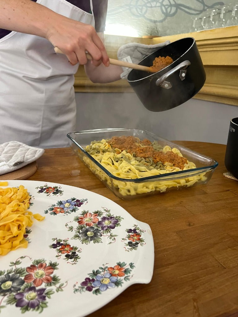 Momento del condimento delle tagliatelle fresche con il ragù bolognese denso e profumato appena tolto dal fuoco.
