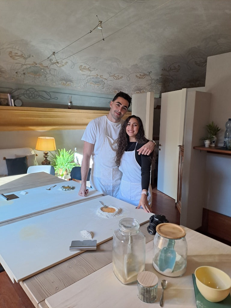 Una giovane coppia sorride durante un corso di cucina privato nella cucina accogliente di DavVero Kitchen.